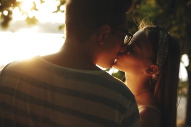 Güneşe karşı öpüşen neşeli genç bir çiftin yakın portresi.