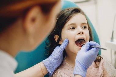Pediatrik stomatolojide onuncu muayeneyi yapan küçük tatlı bir kızın fotoğrafını çek..