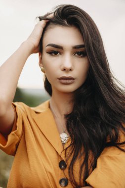 Kameraya bakan çekici bir esmerin yakın portresi. Gerçekten genç bir kız. Doğada ciddi bir şekilde poz veriyor..