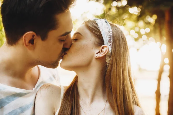 Close up de um jovem casal se beijando contra o pôr do sol. Casal namoro — Fotografia de Stock