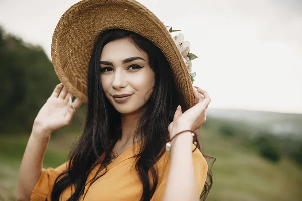 Outdoor shot of a attractive woman looking at camera. Beautiful young girl posing at camera outdoor on a field smiling.