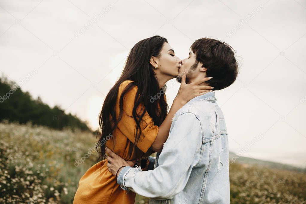 Outdoor shot of a romantic couple kissing outdoor. Lovely young caucasian man and woman embracing and kissing while dating.