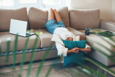 İnternetten ders aldıktan sonra yastıkla kanepede yatan sıkıcı beyaz kadın.