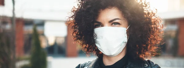 Närbild foto av en lockigt hårig kvinna bär en skyddande mask utanför och tittar på kameran — Stockfoto