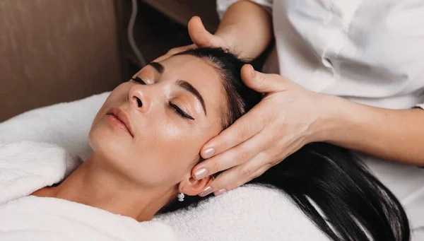 Nahaufnahme von einer Kopfmassage mit einer jungen brünetten Frau mit geschlossenen Augen im Wellness-Salon — Stockfoto