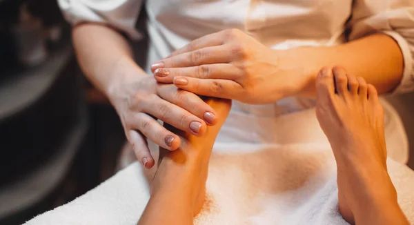 Massagista caucasiano cuidadoso que tem um procedimento de spa de massagem nos pés no salão profissional — Fotografia de Stock