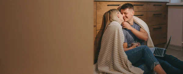 Härligt par poserar i köket på golvet med en dator samtidigt kyssas — Stockfoto