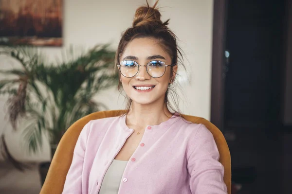 Bella donna caucasica con gli occhiali sorridente alla macchina fotografica dentata mentre indossa una giacca rosa — Foto Stock