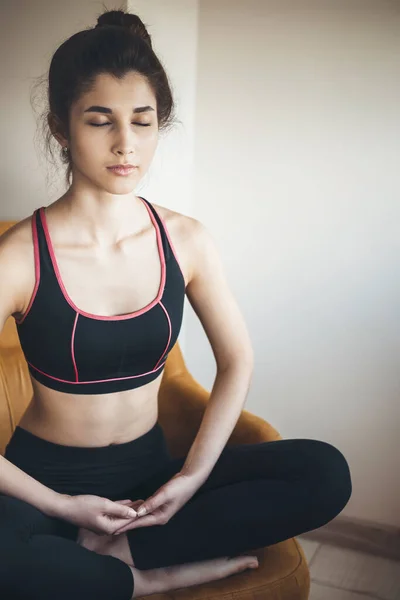 Jeune fille caucasienne vêtue de vêtements de sport fait du yoga dans le sol assis avec les jambes croisées et les yeux fermés — Photo