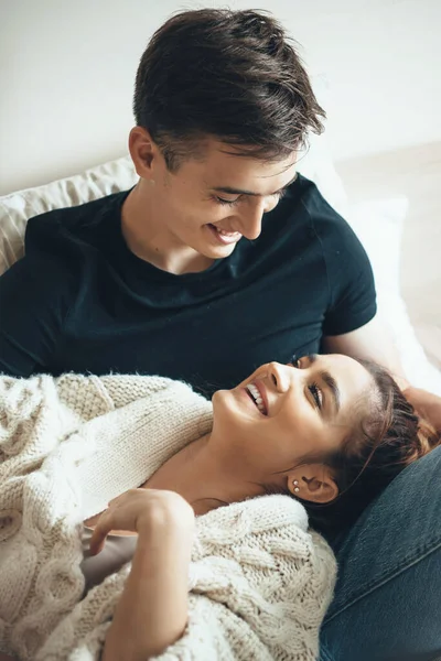 Chica joven con un suéter de punto sonriendo a su amante acostado en sus rodillas —  Fotos de Stock