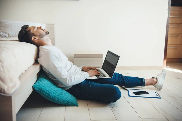 Hombre de negocios caucásico con barba sentado en el suelo y durmiendo mientras trabaja en la computadora con un poco de documentación —  Fotos de Stock