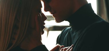 Beyaz bir adam kız arkadaşını kucaklıyor ve güneşin altında samimi bir anda onun yüzünü tutuyor.