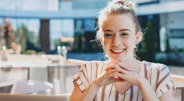 Donna d'affari zenzero con lentiggini in posa in una caffetteria sorridente alla macchina fotografica — Foto Stock