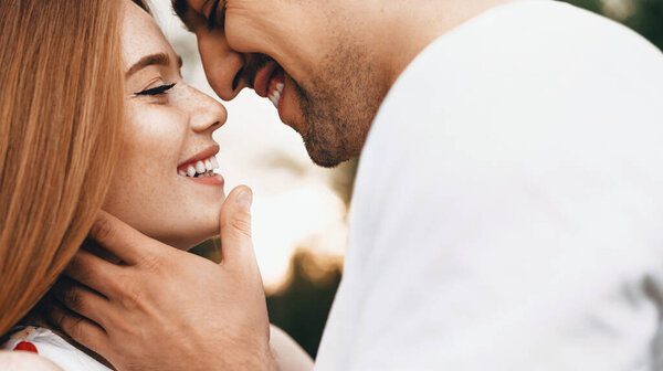 Close up photo of a caucasian woman with red hair and freckles dressed in a white clothes and her lover embracing and kissing