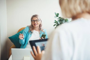 Üst düzey beyaz kadın, dizüstü bilgisayar kullanırken ve gözlük takarken evde toplantı yapıyor.