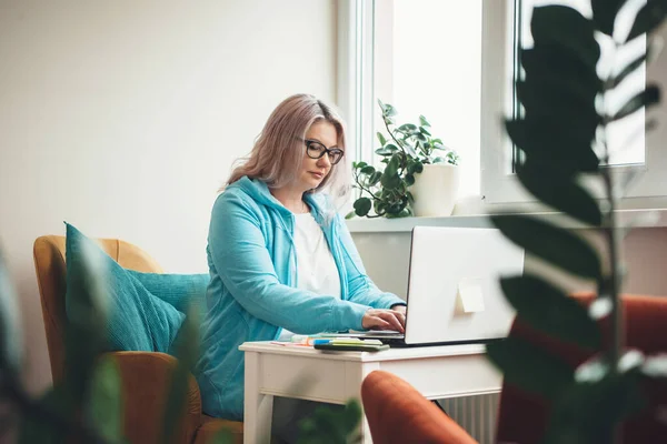 Upptagen seniorkaukasisk affärskvinna som arbetar på en bärbar dator med glasögon och blont hår — Stockfoto