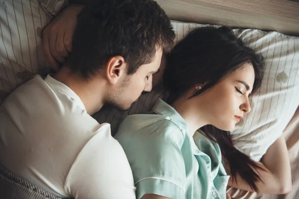 Charmant couple caucasien dormant ensemble dans leur lit embrassant et se reposant — Photo