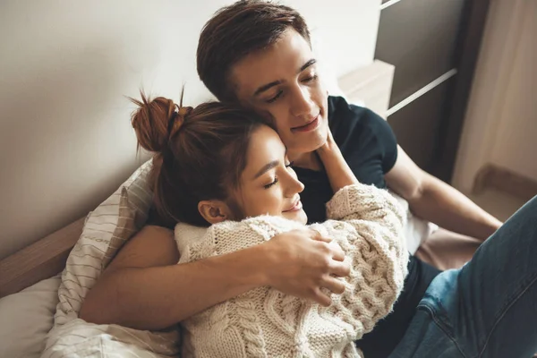 Señora caucásica con suéter de punto está abrazando a su amante en la cama con los ojos cerrados —  Fotos de Stock