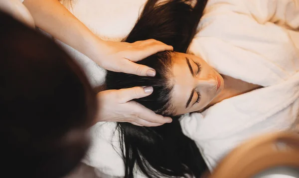 Kaukasisk kvinna med långt svart hår ligger och har en spa huvud massage förfarande — Stockfoto