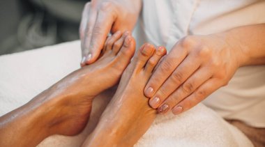 Beyaz bir kadının profesyonel bir kaplıca salonunda ayak masajı yaparken yakın plan fotoğrafı.