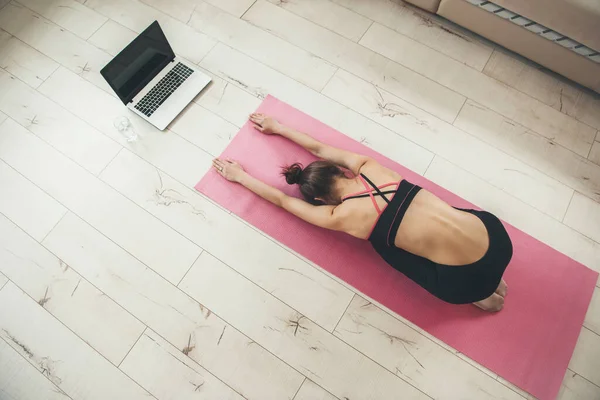 Foto vista superior de una mujer caucásica practicando yoga en casa usando ropa deportiva y usando un portátil en el suelo — Foto de Stock