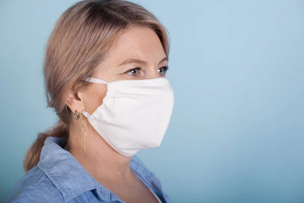 Seniorin mit medizinischer Maske im Gesicht posiert auf blauer Studiowand mit freiem Platz — Stockfoto