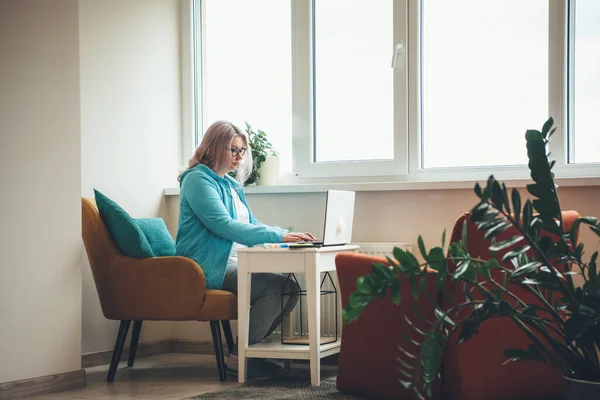 Concentrated senior blond woman working remotely at the laptop during the lockdown — Stock Photo, Image