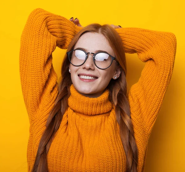 Foto de cerca de una mujer caucásica con anteojos y pecas sonriendo a la cámara en un suéter amarillo de punto — Foto de Stock