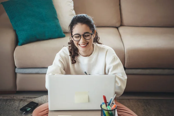 Härligt kaukasiska flicka leende och bära glasögon när du använder laptop och hemundervisning — Stockfoto