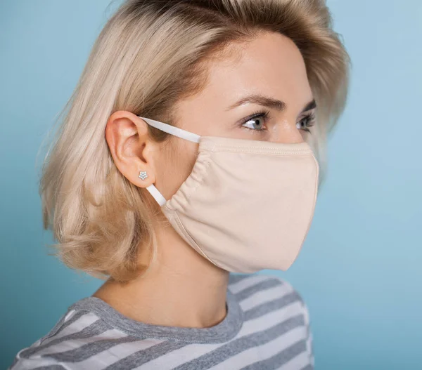 Nahaufnahme Foto einer schönen blonden Dame mit medizinischer Maske auf dem Gesicht posiert auf einer blauen Studiowand — Stockfoto