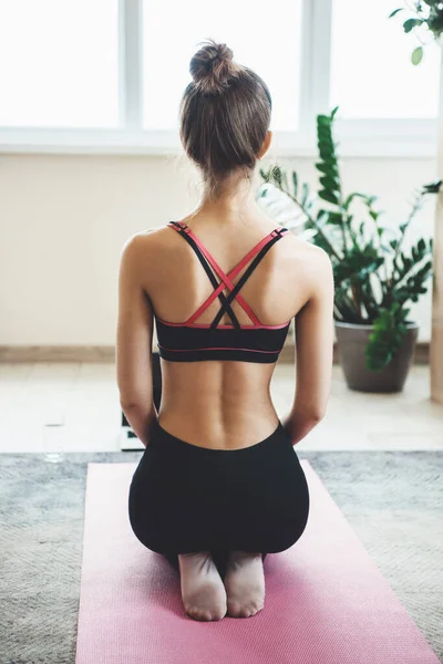 Foto vista posterior de una mujer caucásica en ropa deportiva sentada en el suelo frente a la computadora portátil y meditando — Foto de Stock