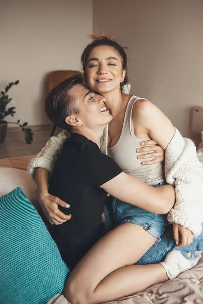 Sexy casal caucasiano sorrindo na cama enquanto abraçando e se divertindo — Fotografia de Stock