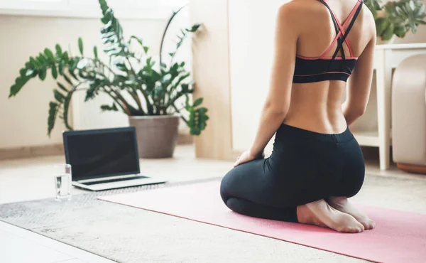 Vista posterior de la foto de una mujer caucásica en uso activo utilizando un ordenador portátil en el suelo haciendo ejercicio — Foto de Stock