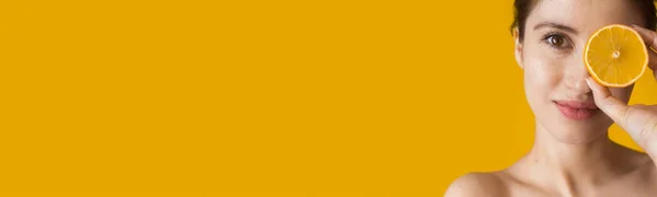 Белая женщина с обнаженными плечами, позирующая с оранжевым покрытием на желтой стене студии с свободным пространством — стоковое фото