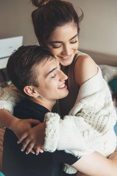 Charmant couple mignon embrassant à la maison assis sur le canapé et sourire avec les yeux fermés — Photo