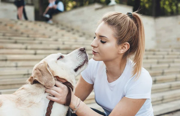 Cute caucasian woman kissing her golden retriever while walking outside — Stock Photo, Image