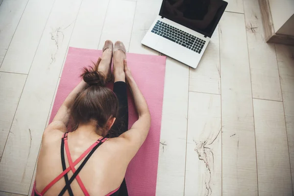 Foto vista dall'alto di una donna caucasica in abbigliamento sportivo che fa yoga a casa sul pavimento utilizzando un computer portatile — Foto Stock