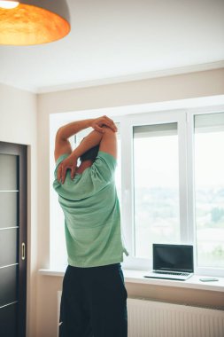 Beyaz bir adamın arka plan fotoğrafı. Evinin önünde gerinen ve spor dersi için hazırlanan beyaz bir adam.