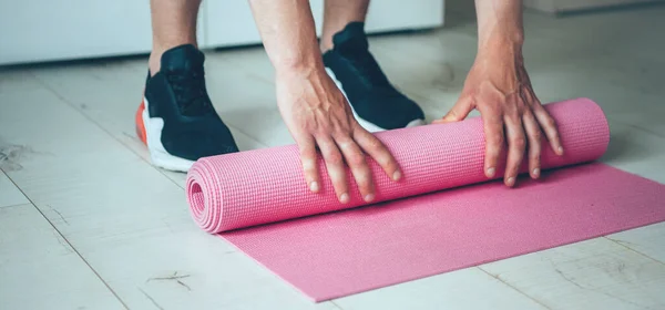 Uomo caucasico finire la sua lezione di yoga raccogliendo il tappeto dopo l'esercizio a casa — Foto Stock