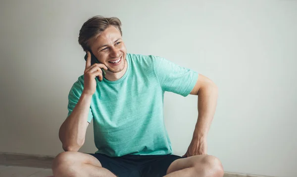 Leende blond man som tar en paus under konditionslektionen hemma och pratar i telefon — Stockfoto