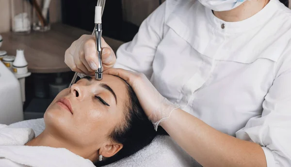 Foto vista lateral de una mujer caucásica que se somete a procedimientos especiales de piel en su cara en un salón de spa con nuevas tecnologías — Foto de Stock