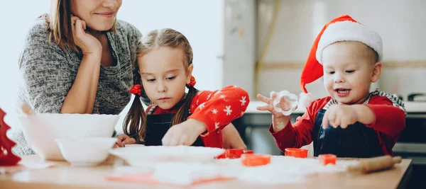 Famiglia caucasica che si prepara per Natale indossando vestiti di festa e biscotti di cottura a casa insieme — Foto Stock
