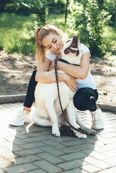 Kaukázusi szőke nő és arany retriever ölelés közben séta a parkban — Stock Fotó