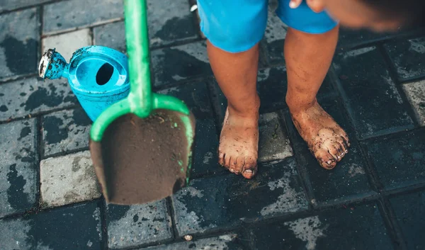 Criança caucasiana suja brincando com brinquedos em casa no jardim com água está pronta para um banho — Fotografia de Stock