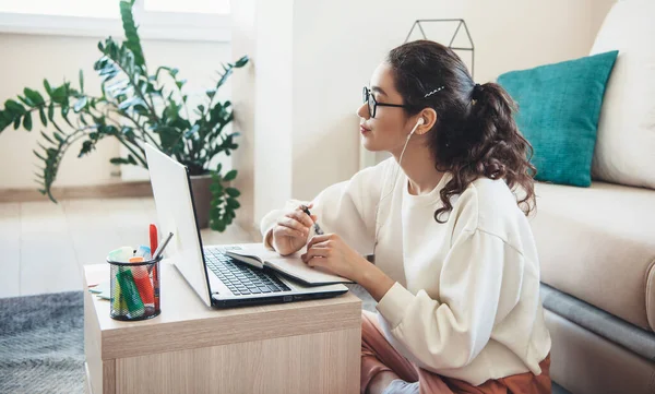 Внимательная белая женщина в очках проводит онлайн-уроки, пользуясь наушниками и ноутбуками — стоковое фото