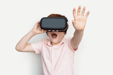 Beyaz bir stüdyo duvarında poz verirken gözlerine kulaklık takmış bir kızıl.