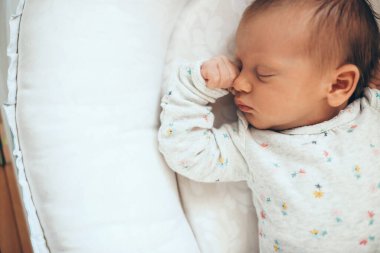 Yeni doğmuş bir bebeğin beyaz bir yatakta uyurkenki fotoğrafı.