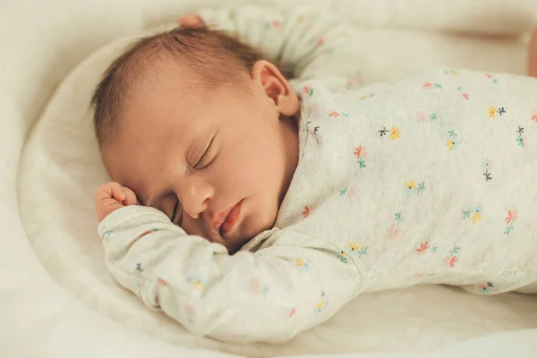 Newborn baby in white warm clothes sleeping in bed totally relaxed and feeling safe