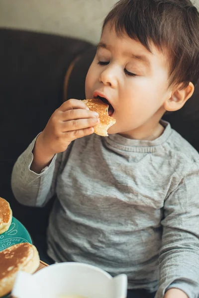 Close up foto de um caucasiano faminto menino comendo panquecas em casa — Fotografia de Stock