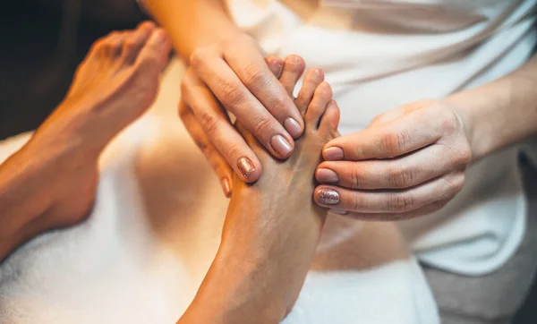 Upper view photo of a caucasian spa worker having a feet massage session at the spa salon with a young client